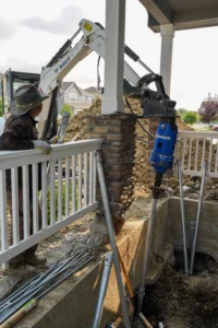 Fort August Construction installing a helical pier under a residential front porch for foundation stabilization