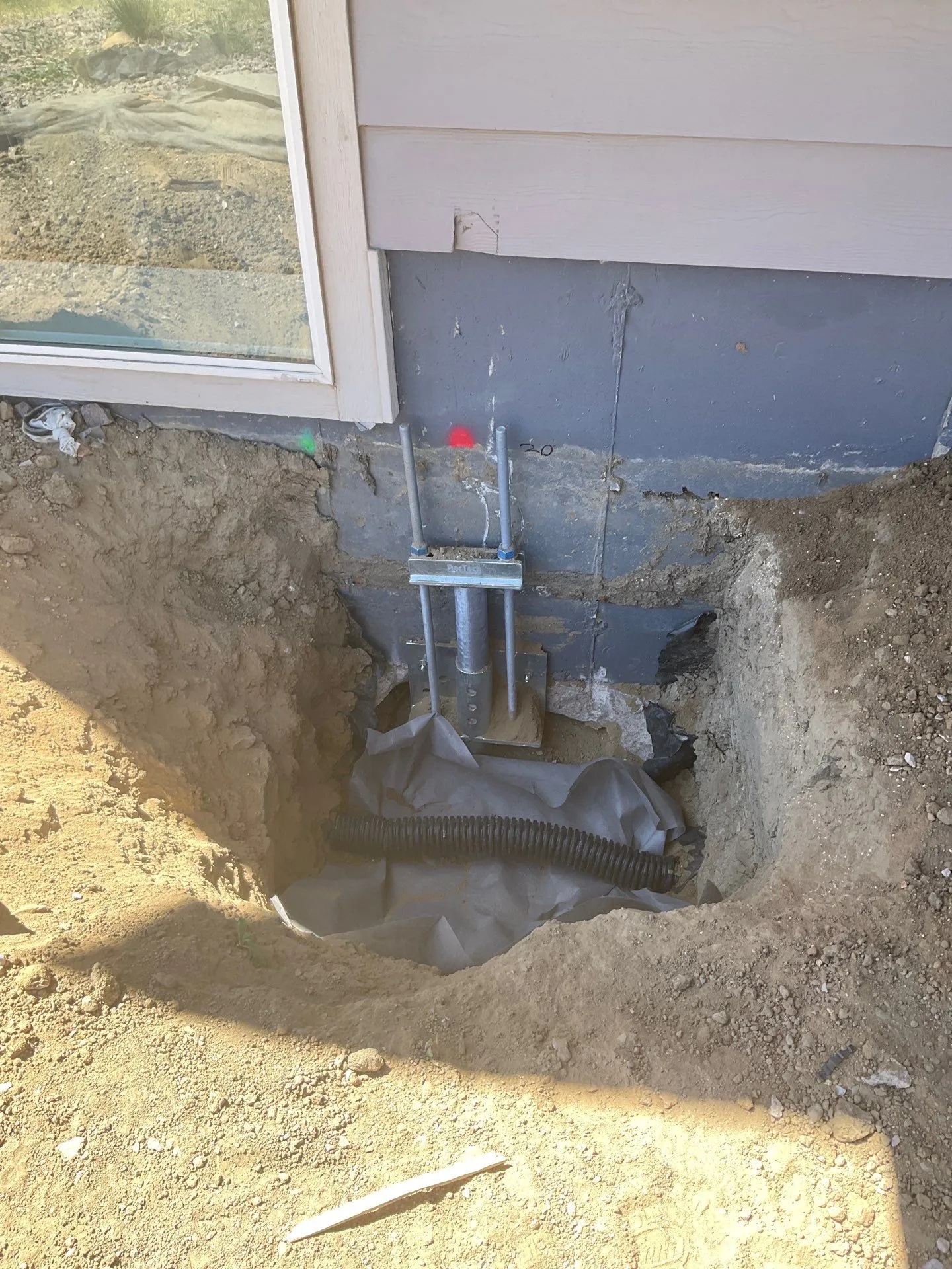 Helical pier installation in Colorado Springs attached to foundation footing for structural stabilization.