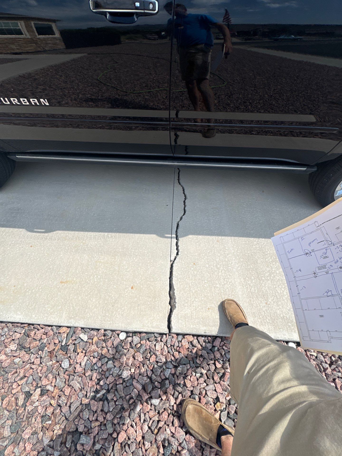 Cracked concrete driveway running toward a black SUV, caused by expansive soil movement, at a residential foundation assessment in Cañon City, Colorado.