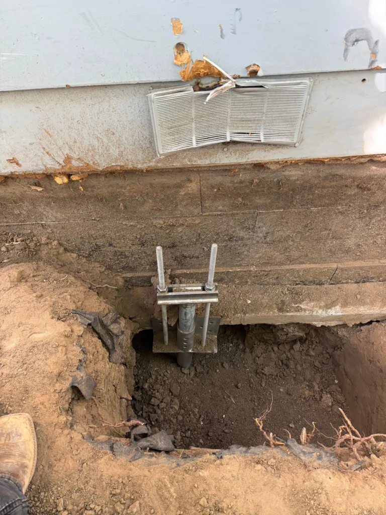 Helical pier assembly and steel foundation bracket in an excavation during foundation stabilization in Longmont by Fort August Foundation