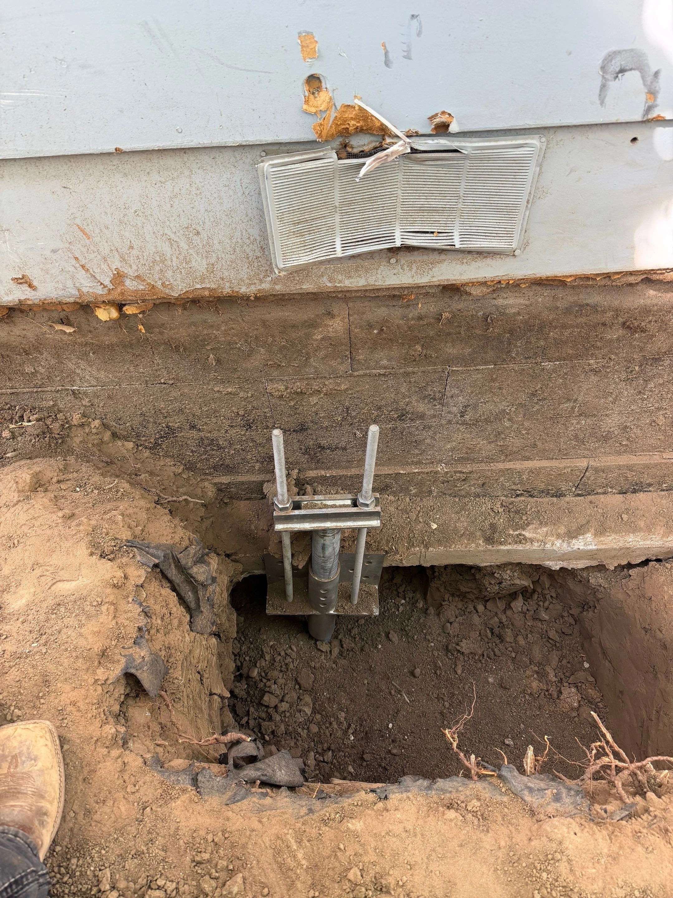 Helical pier assembly and steel foundation bracket in an excavation during foundation stabilization in Longmont by Fort August Foundation