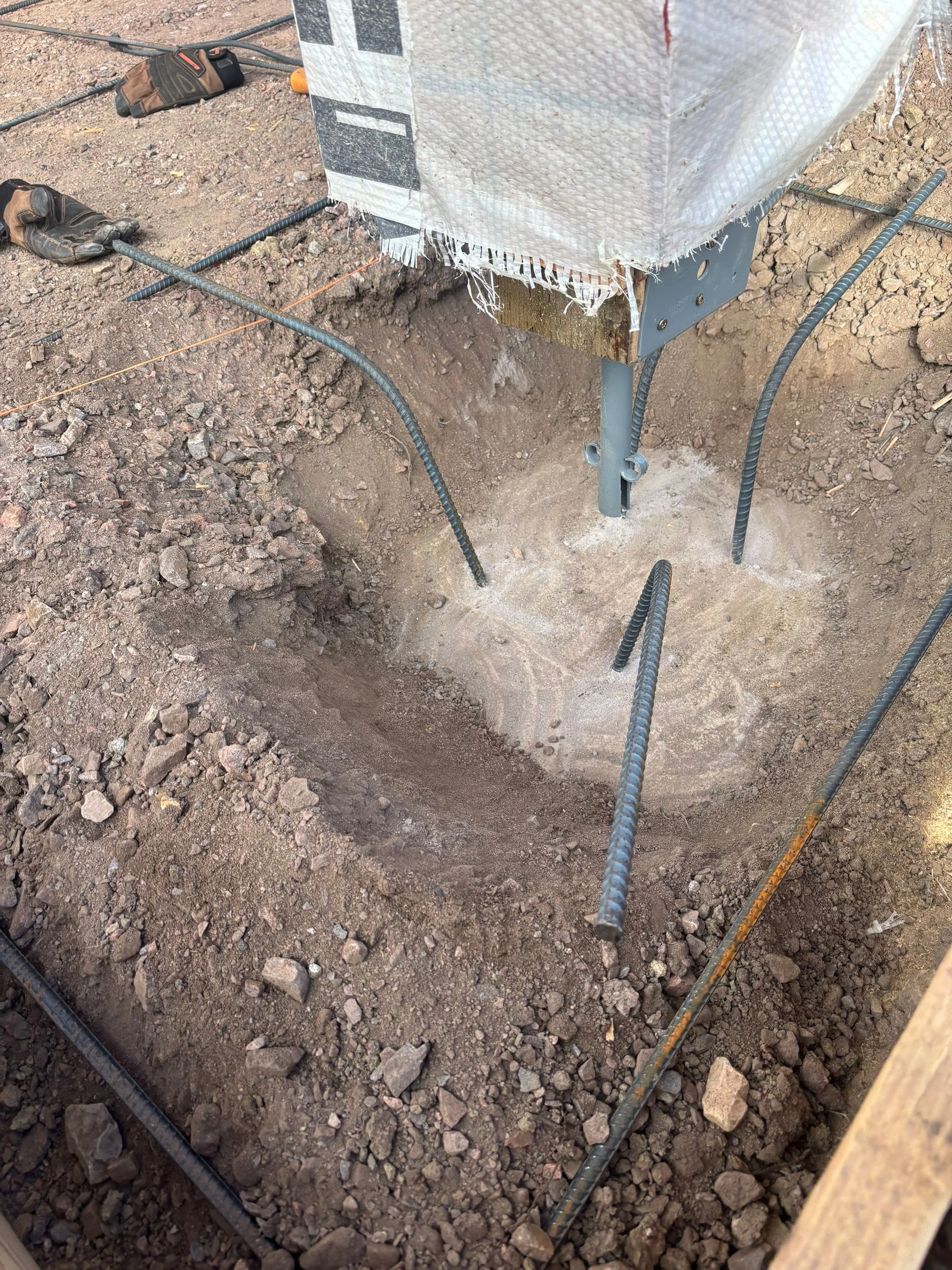 Excavated patio support with reinforcing steel and post connection hardware during foundation stabilization in Cañon City by Fort August Foundation