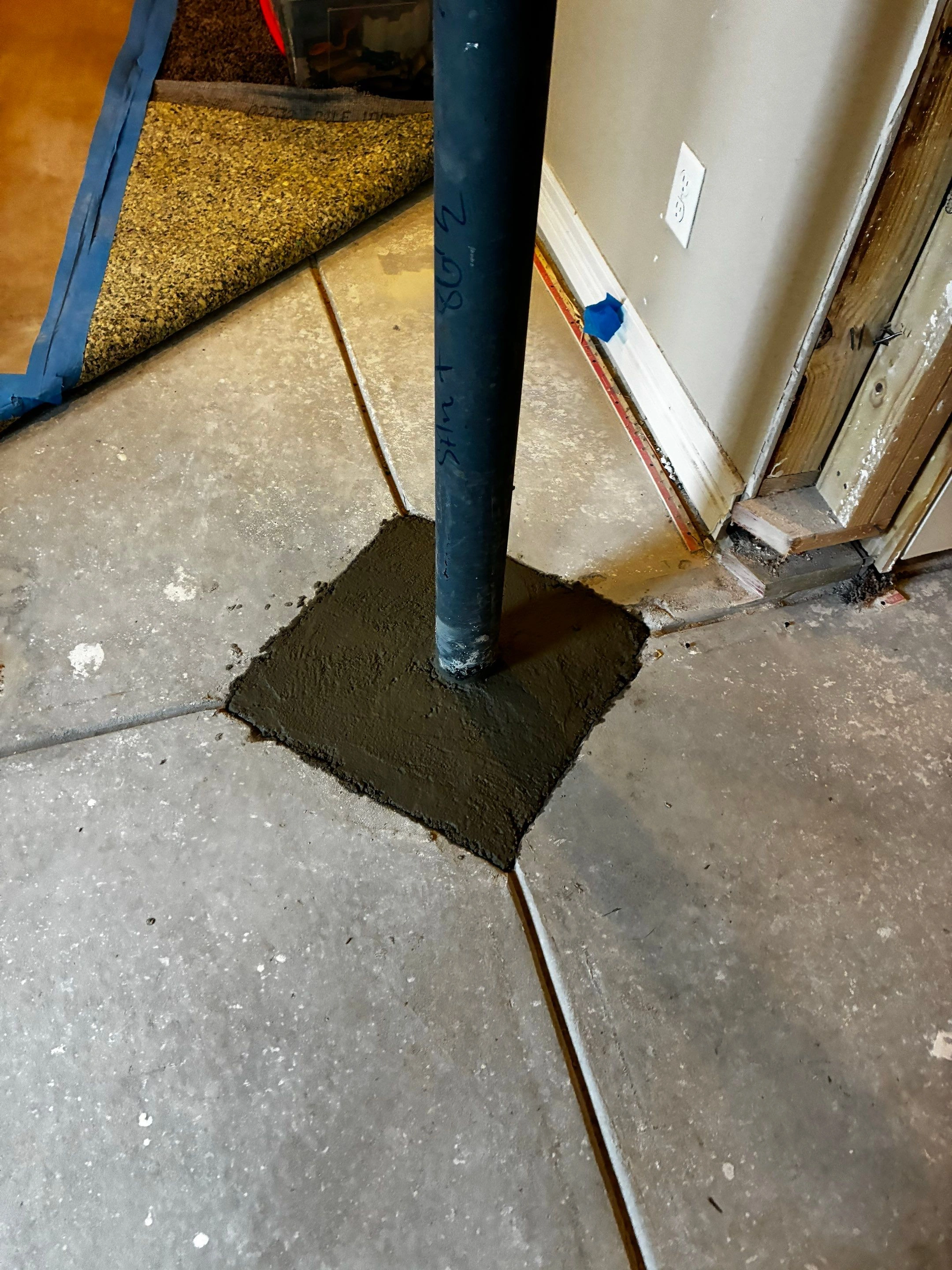 Interior steel support column set into a fresh concrete slab patch during foundation repair by Fort August Foundation in Berthoud