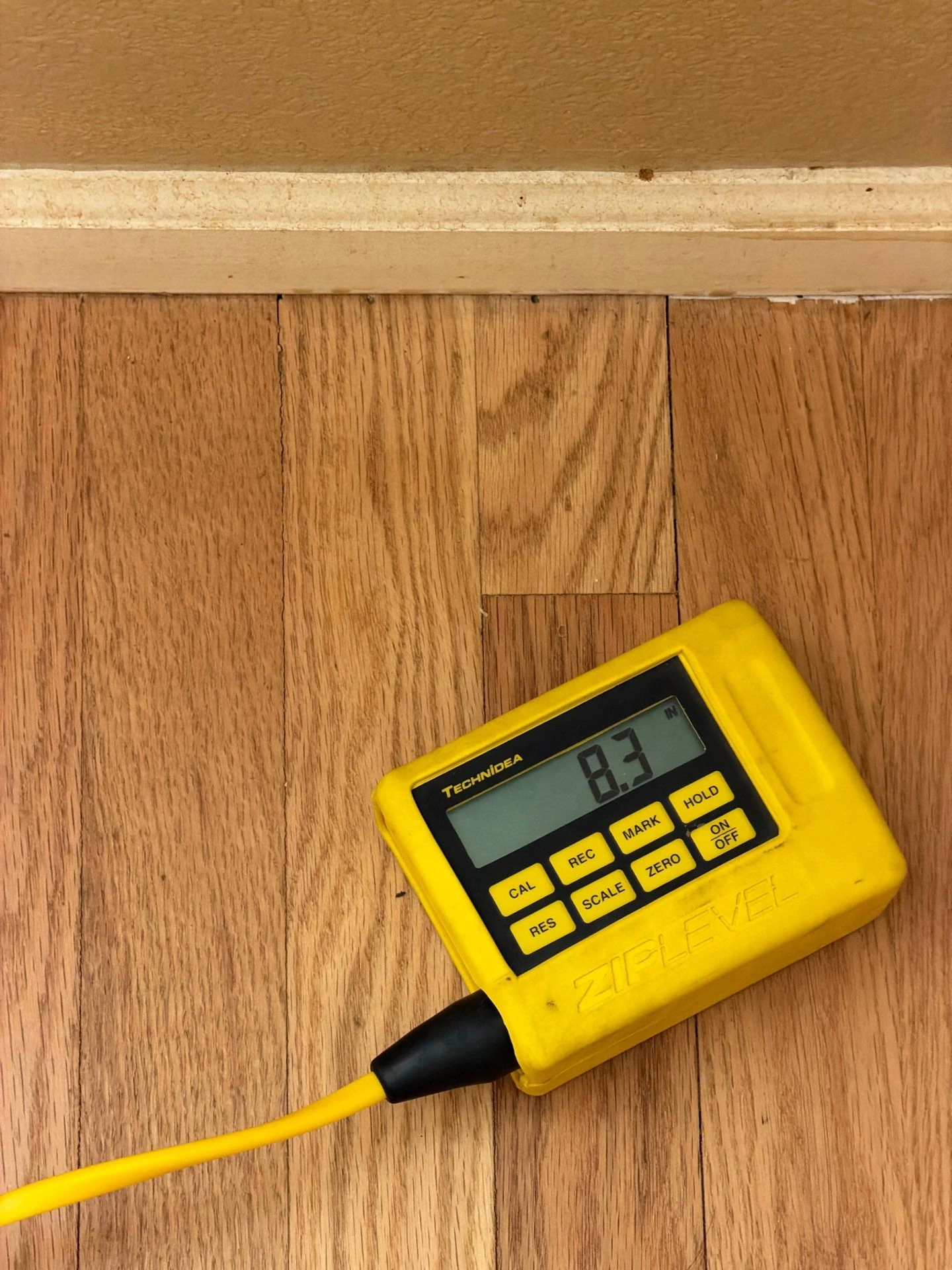 ZipLevel displaying an 8.3-inch floor-height reading during a foundation inspection by Fort August Foundation in Broomfield